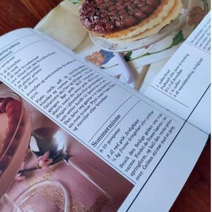 Puede incluir: Un primer plano de una p&aacute;gina de un libro de recetas con una foto de un postre. El postre es una tarta con un relleno marr&oacute;n y una corteza dorada. El texto de la p&aacute;gina est&aacute; en un idioma escandinavo e incluye las palabras "Sommerminne" y "8-10 porsjoner".