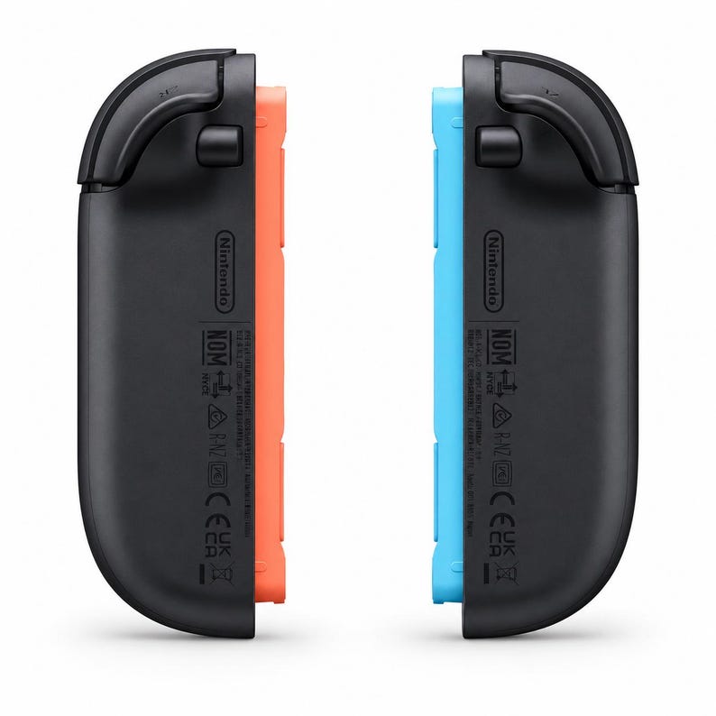 May include: Two black Nintendo Switch Joy-Con controller straps with curved edges. One strap features a bright orange side panel, while the other has a bright blue side panel. Both units display the Nintendo logo and regulatory text markings.