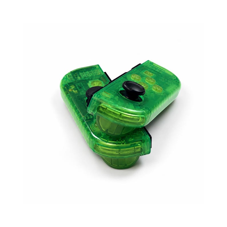 May include: Two transparent green game controllers with black buttons and joysticks are stacked on a white background. The controllers have a rectangular shape with rounded edges and visible internal components.