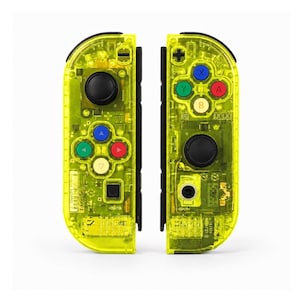 May include: A pair of neon yellow transparent game controllers featuring black joysticks and buttons in red, blue, green, and yellow. The internal electronic components are visible through the clear casing, including various buttons and directional pads.
