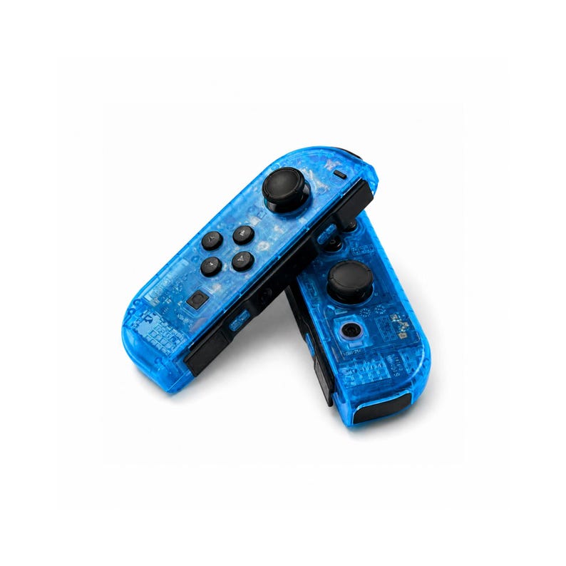 Pu&ograve; includere: Due controller di gioco blu trasparenti con pulsanti e joystick neri. I controller sono angolati l'uno verso l'altro, rivelando i componenti interni. I controller sono progettati per una console di gioco.