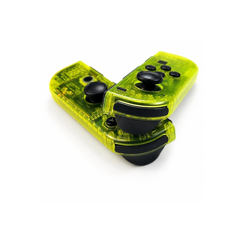 May include: Two neon yellow video game controllers with a transparent shell design. Each controller features black analog sticks, black shoulder buttons, and a set of black circular action buttons. The internal electronic components are visible.