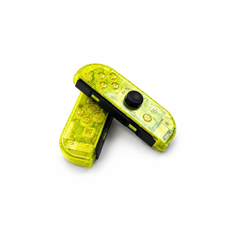 May include: Two video game controllers with a translucent neon yellow shell. Each controller features a black analog stick, a directional pad, four circular action buttons, and additional small function buttons. The internal electronic components are visible through the clear yellow plastic casing.