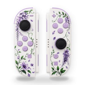 May include: A pair of white game controllers featuring a purple wisteria floral pattern with green vines and leaves. The controllers include black joysticks, purple directional buttons, and standard action buttons labeled A, B, X, and Y.