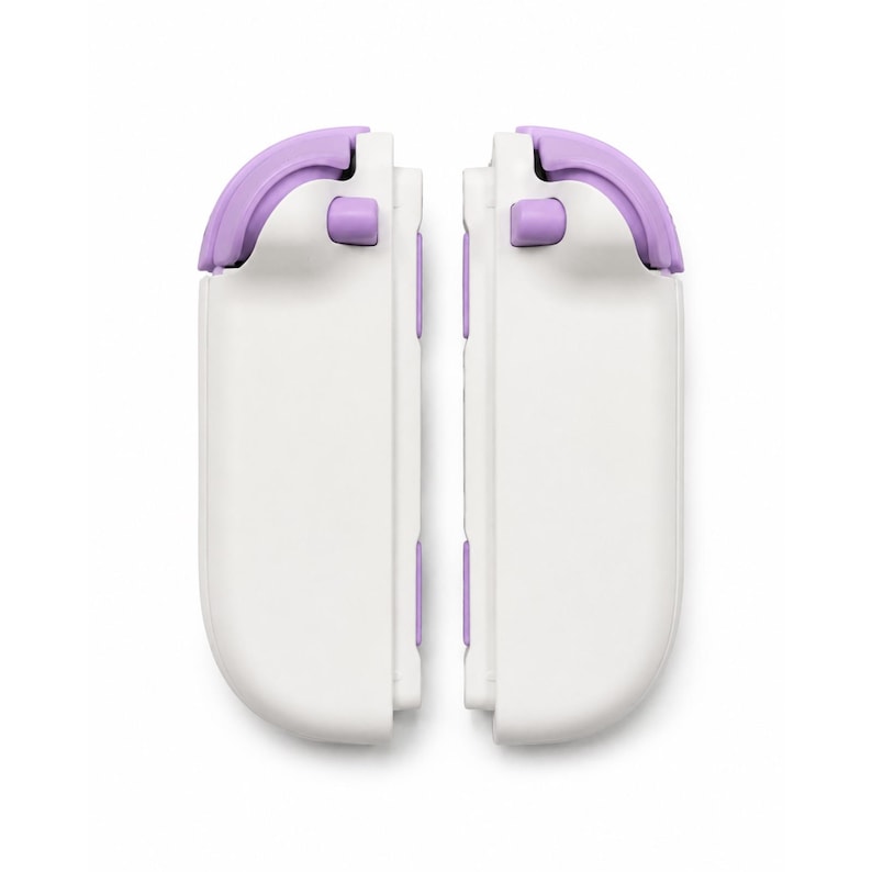Puede incluir: Dos accesorios de mando de juego blancos con bordes redondeados y detalles en color lavanda en los botones superiores y laterales. Estos accesorios de juego rectangulares tienen un acabado liso y est&aacute;n colocados verticalmente uno al lado del otro.