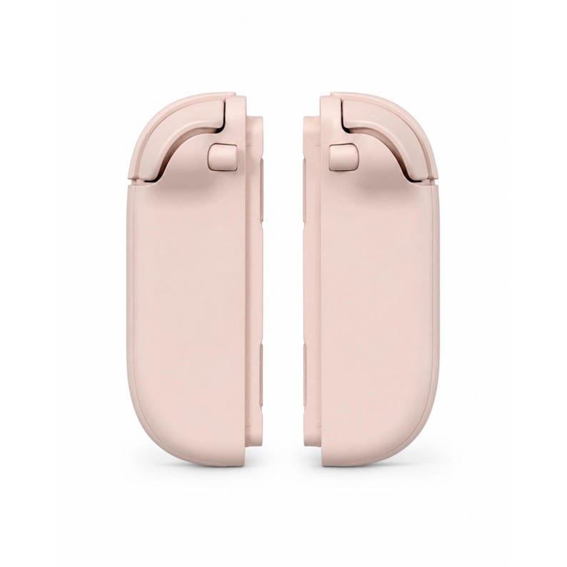 May include: A pair of pale pink gaming controller attachments featuring a smooth, rounded rectangular design with integrated shoulder buttons and triggers. These two matching components are positioned vertically, mirroring each other in a clean, matte finish.