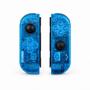 May include: Two transparent blue game controllers with black buttons and directional pads. The controllers are designed to be attached to a gaming console. The internal components are visible through the translucent plastic.