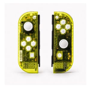 May include: A pair of neon yellow transparent game controllers featuring white buttons and joysticks. The left controller has a directional pad with four arrow buttons, while the right controller has four lettered action buttons labeled A, B, X, and Y.