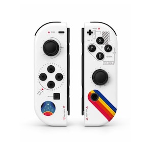 May include: Two white game controllers featuring black buttons and joysticks. The left controller has a circular planet graphic and text including SCAN, THRUST, and PWR DIST. The right controller has A, B, X, Y buttons, text including MODE, EXIT, LOCK, FLT CNTRL, and a diagonal rainbow stripe.