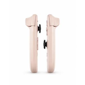 May include: Two pale pink gaming controllers positioned side by side. Each controller features a smooth, elongated body with a prominent black analogue stick protruding from the centre, along with integrated shoulder buttons and circular control buttons.