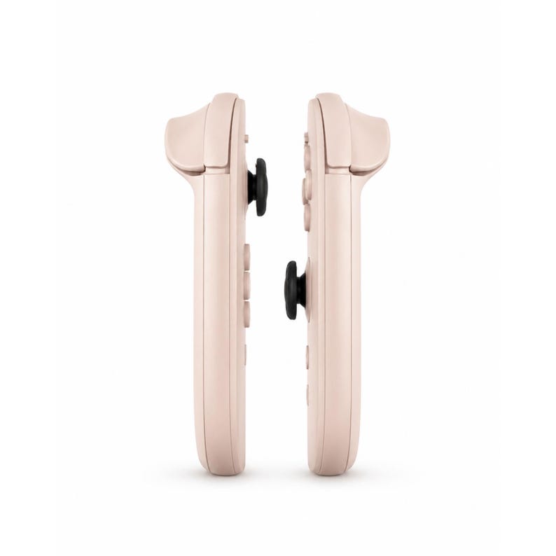 May include: Two pale pink gaming controllers positioned side by side. Each controller features a smooth, elongated body with a prominent black analogue stick protruding from the centre, along with integrated shoulder buttons and circular control buttons.