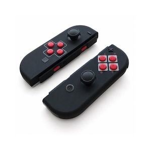 Pode incluir: Dois comandos de jogo pretos com bot&otilde;es vermelhos e joysticks pretos sobre um fundo branco. Os comandos t&ecirc;m uma forma retangular com bordas arredondadas. Os bot&otilde;es est&atilde;o dispostos em forma de cruz e quadrado.