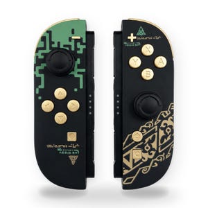 May include: Two black game controllers featuring gold buttons and joysticks. The left controller has a green pixelated pattern and gold symbols. The right controller displays gold geometric patterns, gold A, B, X, Y buttons, and a small green eye icon.