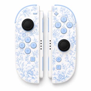 May include: A pair of white video game controllers featuring a light blue floral pattern. Each controller has a black circular joystick, light blue directional buttons, and light blue action buttons labelled A, B, X, and Y, along with home and capture icons.