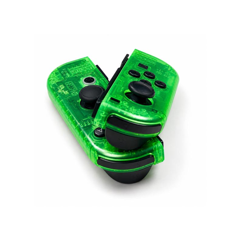 May include: Two transparent green game controllers with black buttons and joysticks are stacked on top of each other. The controllers have a circuit board design visible through the plastic. The controllers are for a gaming console.