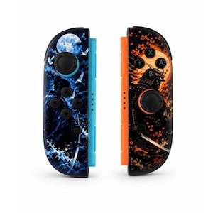 May include: Two game controllers featuring custom graphic skins. The left controller has a blue side rail and a blue-toned scene of a samurai with a sword, moon, and birds. The right controller has an orange side rail and an orange-toned samurai scene.