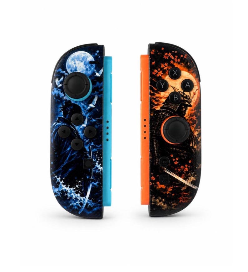 May include: Two game controllers featuring custom graphic skins. The left controller has a blue side rail and a blue-toned scene of a samurai with a sword, moon, and birds. The right controller has an orange side rail and an orange-toned samurai scene.