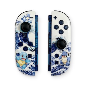 May include: A pair of white video game controllers featuring a blue and white wave pattern inspired by traditional Japanese art. The left controller displays a Squirtle character, while the right controller features a Blastoise character.