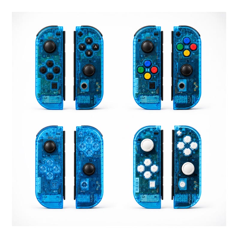 Pu&ograve; includere: Quattro paia di controller di gioco blu trasparenti. Ogni controller ha un diverso layout di pulsanti, con pulsanti neri, bianchi e colorati. I controller sono progettati per una console di gioco e sono visualizzati su uno sfondo bianco.