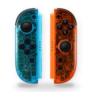 May include: A pair of wireless game controllers featuring a transparent blue shell on the left and a transparent orange shell on the right. Both controllers include black analog sticks, directional buttons, and action buttons labeled A, B, X, and Y.