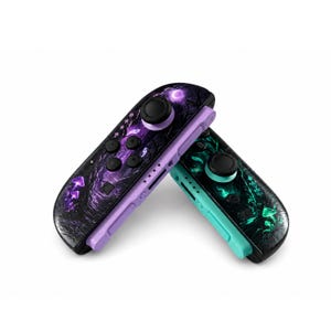 May include: Two game controllers featuring a dark forest theme with glowing purple and teal mushrooms. The left controller has a light purple side rail, while the right controller has a teal side rail. Both controllers include black joysticks and buttons.