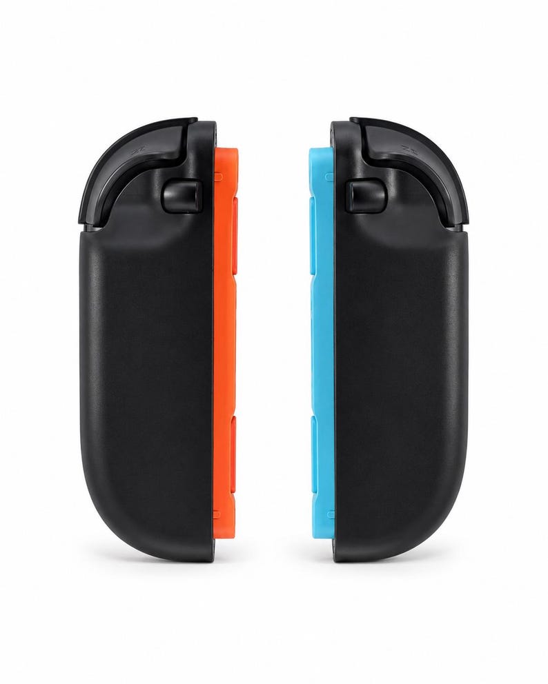 May include: Two black gaming controller attachments, each featuring a curved outer shell and a top shoulder button. One attachment has a bright orange inner side, while the other has a bright blue inner side, both designed for handheld gaming consoles.