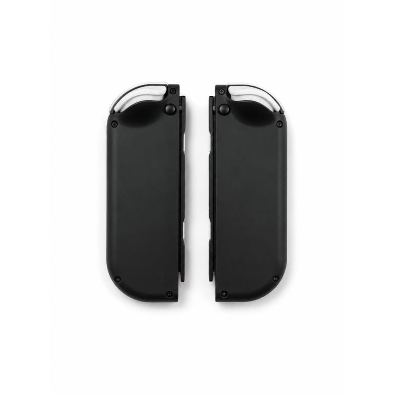 May include: A pair of black wireless game controllers featuring a smooth matte finish, rounded edges, and white shoulder buttons positioned at the top. Each controller has a vertical rectangular shape with visible circular buttons and ports.