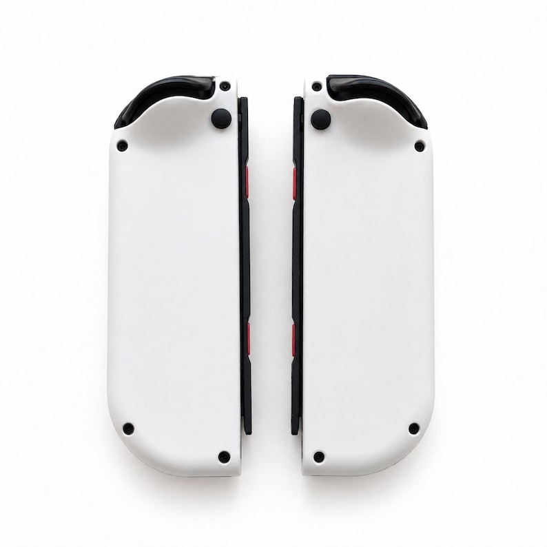 Pode incluir: Dois controles de jogo brancos e pretos, cada um com uma parte superior preta, bot&otilde;es pretos e detalhes em vermelho. Os controles est&atilde;o posicionados lado a lado em um fundo branco.