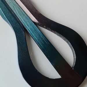 May include: A teal, blue, and silver-colored metal musical instrument called a  'thumb piano' or 'kalimba'.