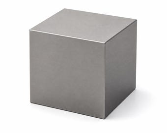 May include: A solid, metallic cube with a smooth, matte gray finish. The object features sharp, clean edges and flat, uniform surfaces on all visible sides, presenting a geometric form with a consistent, neutral tone and a reflective, polished appearance.