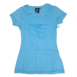 May include: A light blue t-shirt with a gathered detail on the front. The shirt has short sleeves and a scoop neck. A small tag is attached to the sleeve. The shirt is made of a soft, lightweight fabric.