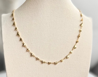 Könnte beinhalten: Eine goldene Halskette mit einer zarten Kette und kleinen Herzanhängern.