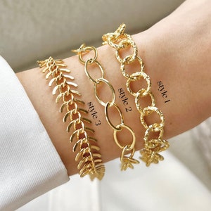 May include: Three gold chain bracelets stacked on a wrist. The top bracelet is labeled "Style 1", the middle bracelet is labeled "Style 2", and the bottom bracelet is labeled "Style 3".