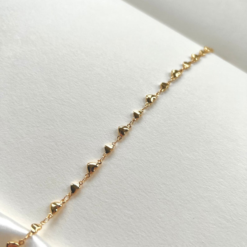 May include: A gold chain bracelet with small heart-shaped charms.