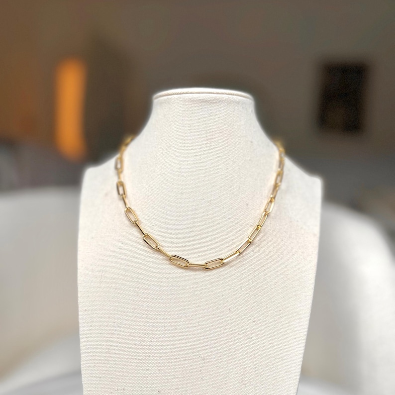 K&ouml;nnte beinhalten: Eine goldene Kettenkette mit einem einfachen, verlinkten Design. Die Kette besteht aus ovalen Gliedern.