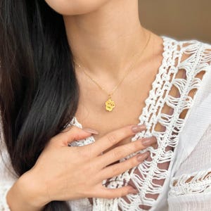 May include: A gold chain necklace with a small gold paw print pendant. The pendant has the word "Lola" engraved on it.