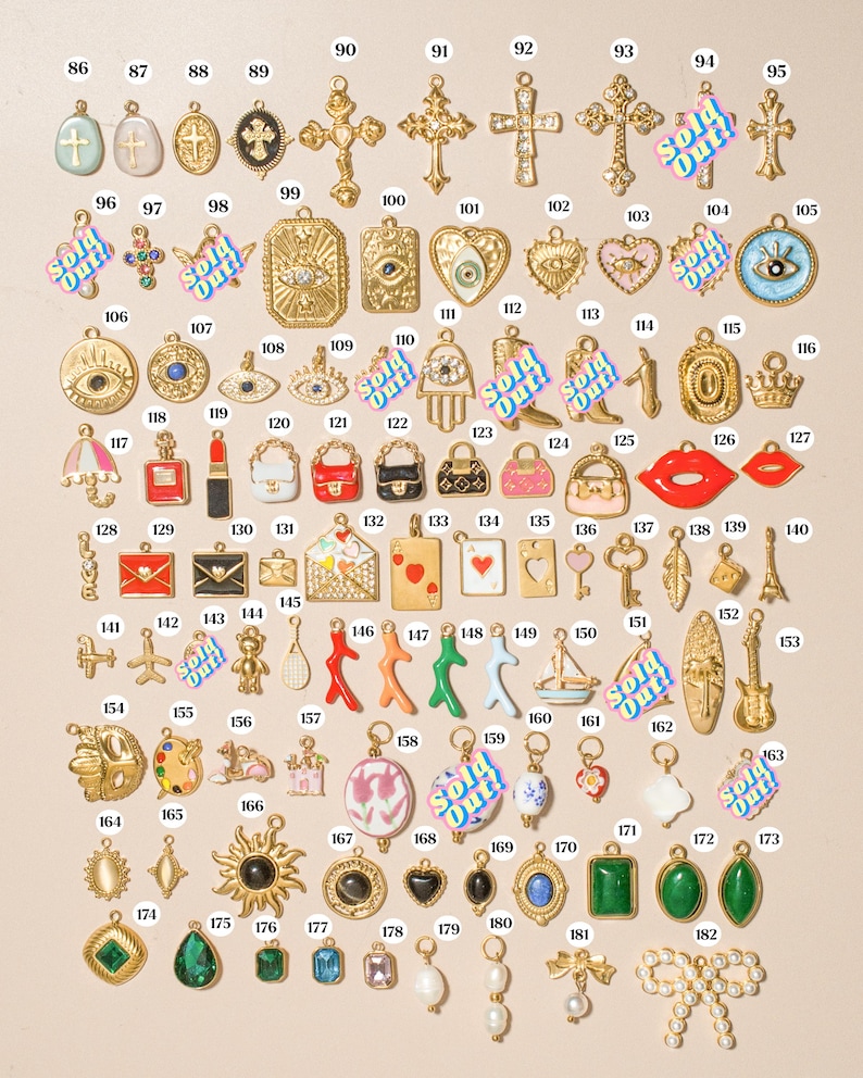 K&ouml;nnte beinhalten: Eine Sammlung verschiedener Metallanh&auml;nger, nummeriert von 86 bis 182, mit verschiedenen Formen wie Kreuzen, Augen, Herzen, Handtaschen, Spielkarten, Tieren und geometrischen Steinen. Einige Anh&auml;nger sind mit dem Text Sold Out in Blau und Pink markiert.