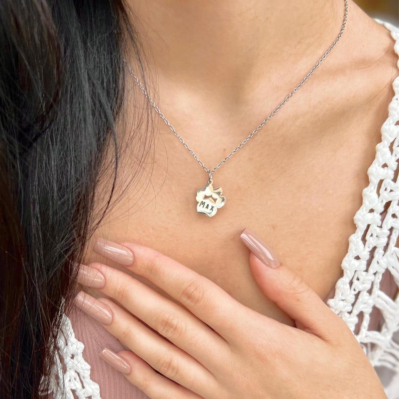 May include: A silver necklace with a paw print charm that says "MAX" on it.