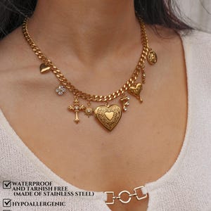 K&ouml;nnte beinhalten: Eine goldfarbene Kette mit mehreren Anh&auml;ngern, darunter ein herzf&ouml;rmiges Medaillon, ein Kreuz, eine Sonne, ein Buchstabe F und eine Blume. Der Text auf dem Bild lautet: WATERPROOF AND TARNISH FREE (MADE OF STAINLESS STEEL), HYPOALLERGENIC, COMES IN A GIFT BOX, ADD A FREE ENGRAVED GIFT MESSAGE CARD AT CHECKOUT.
