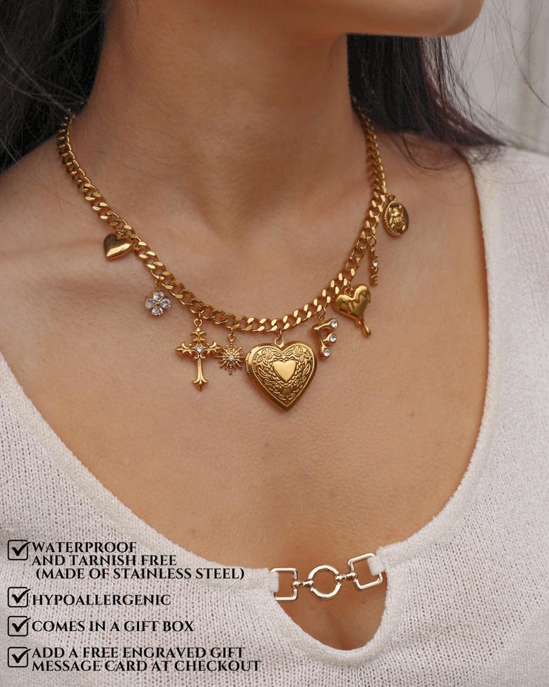 K&ouml;nnte beinhalten: Eine goldfarbene Kette mit mehreren Anh&auml;ngern, darunter ein herzf&ouml;rmiges Medaillon, ein Kreuz, eine Sonne, ein Buchstabe F und eine Blume. Der Text auf dem Bild lautet: WATERPROOF AND TARNISH FREE (MADE OF STAINLESS STEEL), HYPOALLERGENIC, COMES IN A GIFT BOX, ADD A FREE ENGRAVED GIFT MESSAGE CARD AT CHECKOUT.