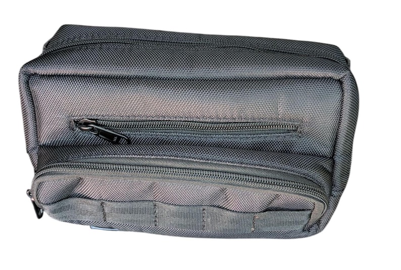 May include: A rectangular, black nylon bag with multiple zipped compartments. The bag has a textured surface and a small pocket on the front. The zips are black. The bag is designed for carrying small items.