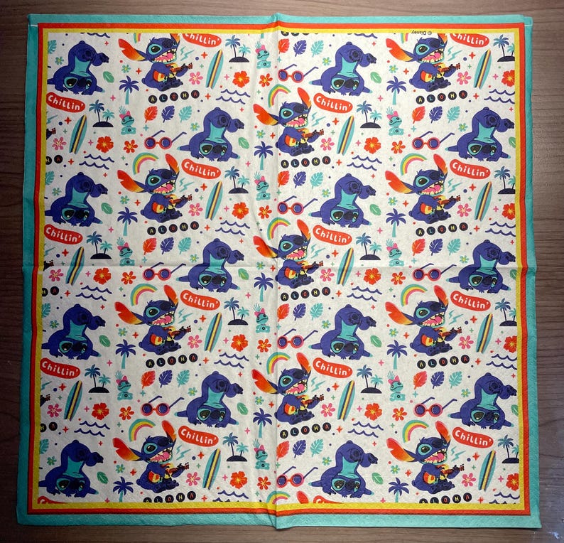 Puede incluir: Un pa&ntilde;uelo blanco con un dise&ntilde;o de personaje azul. El personaje est&aacute; tocando un ukelele y tiene la palabra "Chillin'" encima. El pa&ntilde;uelo tiene un patr&oacute;n repetitivo del personaje, flores y palmeras.