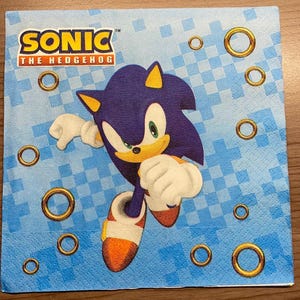 May include: Blue and yellow Sonic the Hedgehog character running on a blue and white checkered background with gold rings. The text "Sonic the Hedgehog" is at the top of the image.