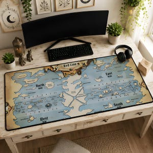 May include: A rectangular desk mat featuring a detailed map of the world from One Piece, including the Red Line, North Blue, East Blue, South Blue, and West Blue. The map has a light blue ocean background with tan landmasses and black text labels.