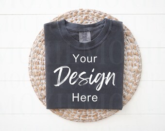 May include: A dark gray t-shirt with a white text overlay that says "Your Design Here" on a woven straw placemat.
