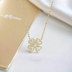 May include: A gold chain necklace with a four-leaf clover pendant encrusted with clear cubic zirconia stones.