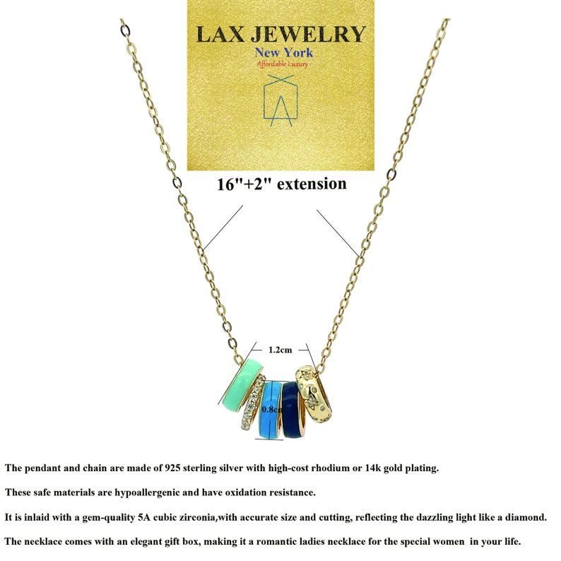 May include: Gold-toned necklace with a pendant featuring five colorful rings. The rings are in shades of blue, green, and gold, with one ring adorned with cubic zirconia. The chain is 16 inches with a 2-inch extension. The LAX JEWELRY logo is visible.
