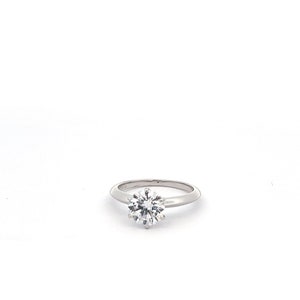 May include: A silver solitaire engagement ring with a round, clear diamond.