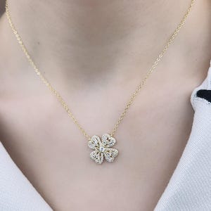 May include: A gold necklace with a delicate four-leaf clover pendant adorned with sparkling clear stones.