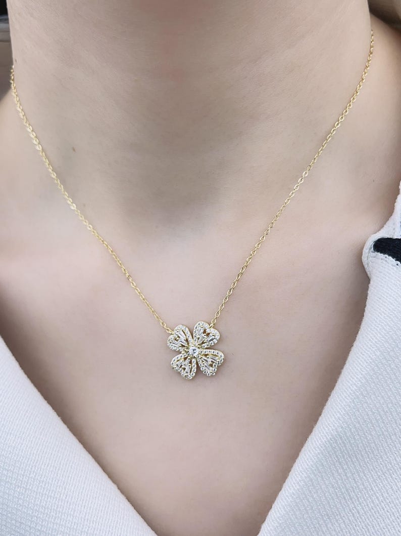 May include: A gold necklace with a delicate four-leaf clover pendant adorned with sparkling clear stones.